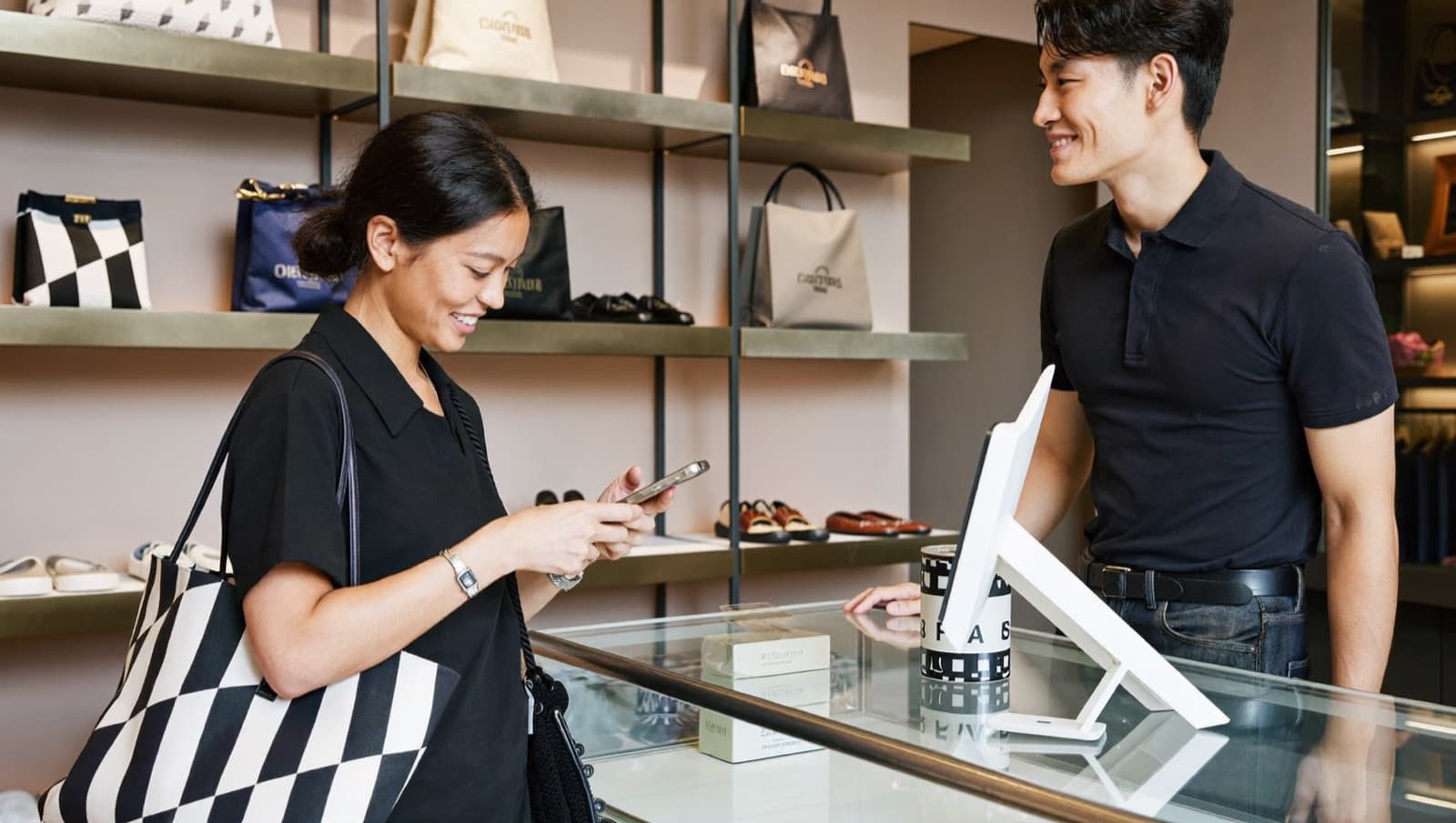 Customer holding her smartphone over a boutique counter while the owner smiles
